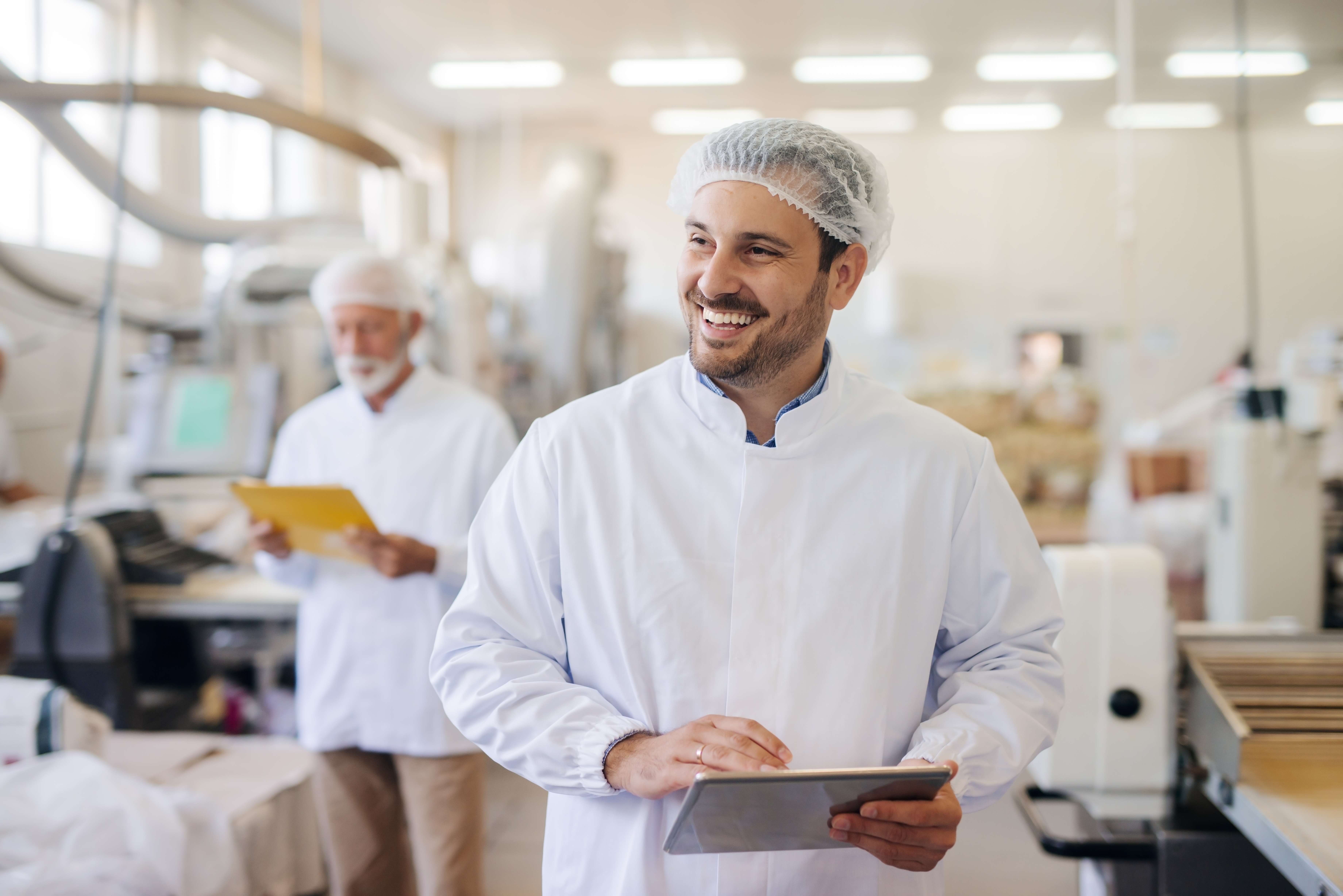 Smiling,Man,Using,Tablet,While,Standing,In,Food,Factory.